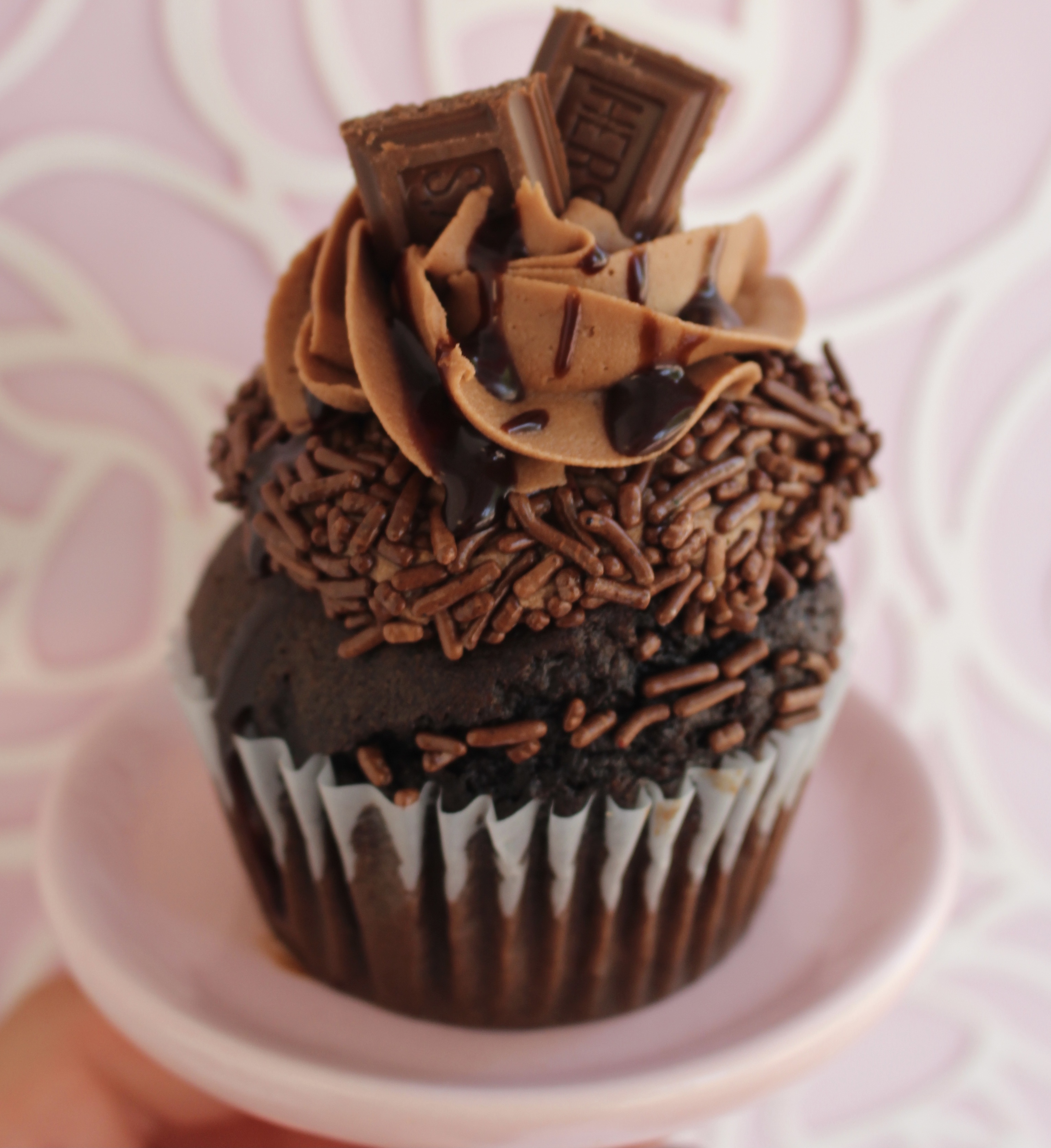 Chocolate cake with a milk chocolate buttercream topping, chocolate sprinkles, chocolate drizzle, and a Hershey bar!